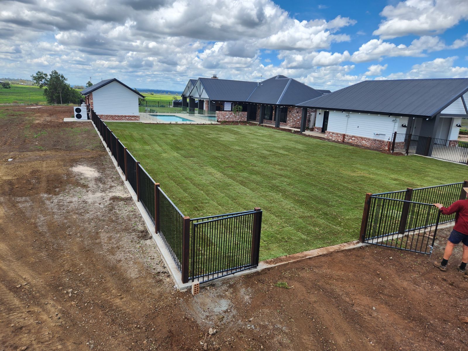 A White Fence is Surrounded by a Lush Green Lawn — Highfields Turf in Highfields, QLD