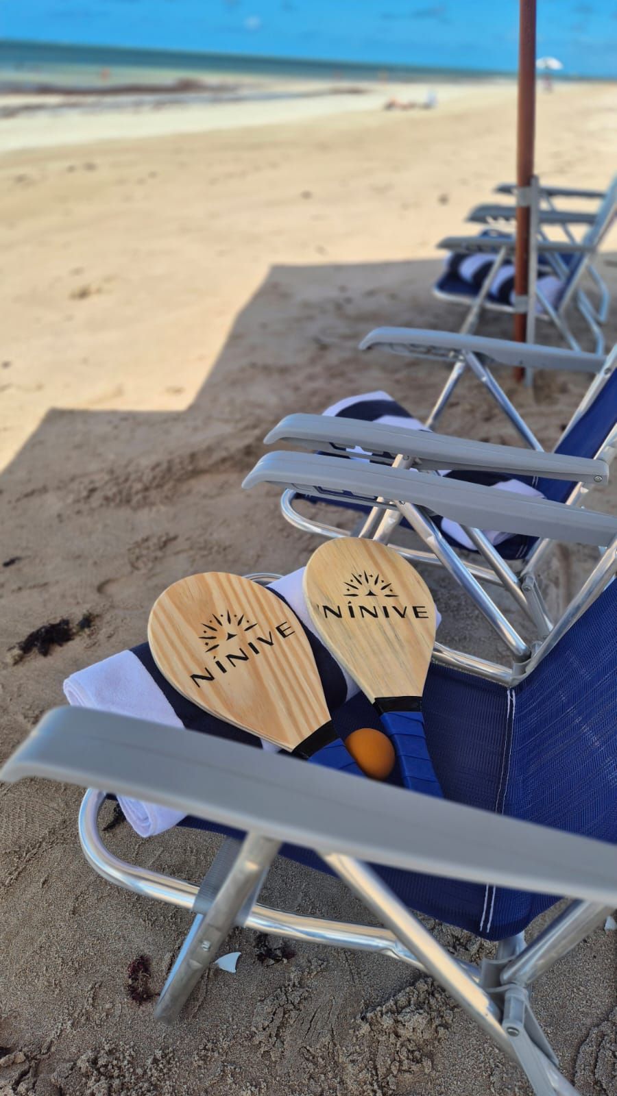 De chinelos numa cadeira de praia junto ao oceano e à areia.