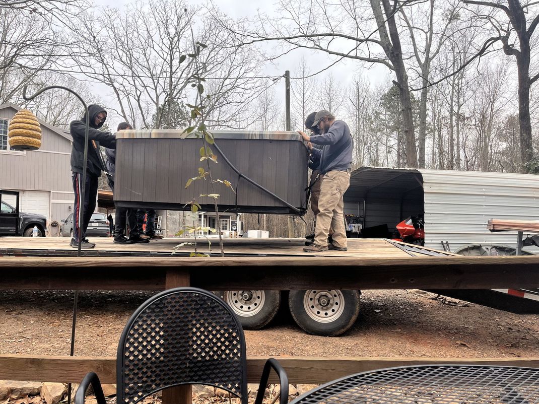 A group of men are working on a hot tub on a trailer