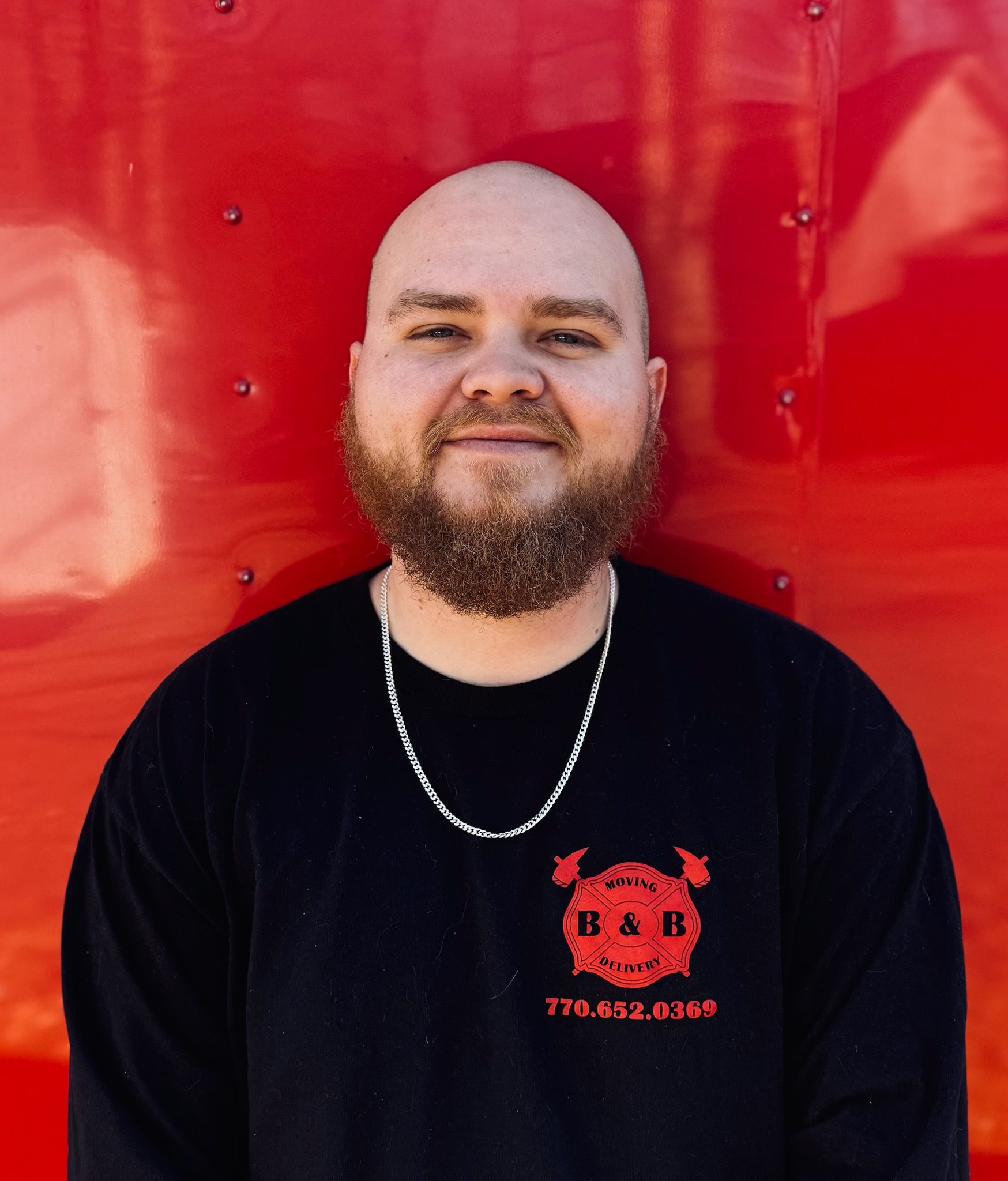 A man with a beard is wearing a black shirt with the letter b on it