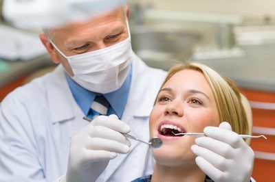 A dentist is examining a woman 's teeth in a dental office.