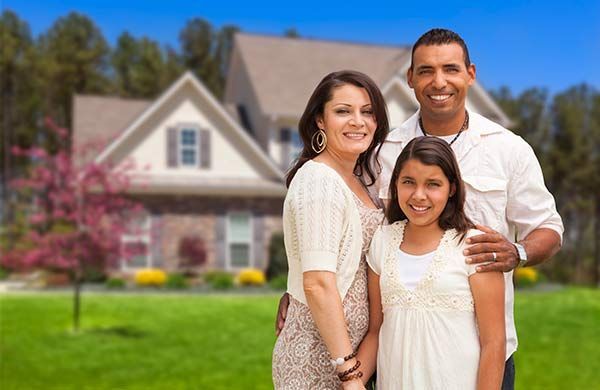 A family is posing for a picture in front of their new home.