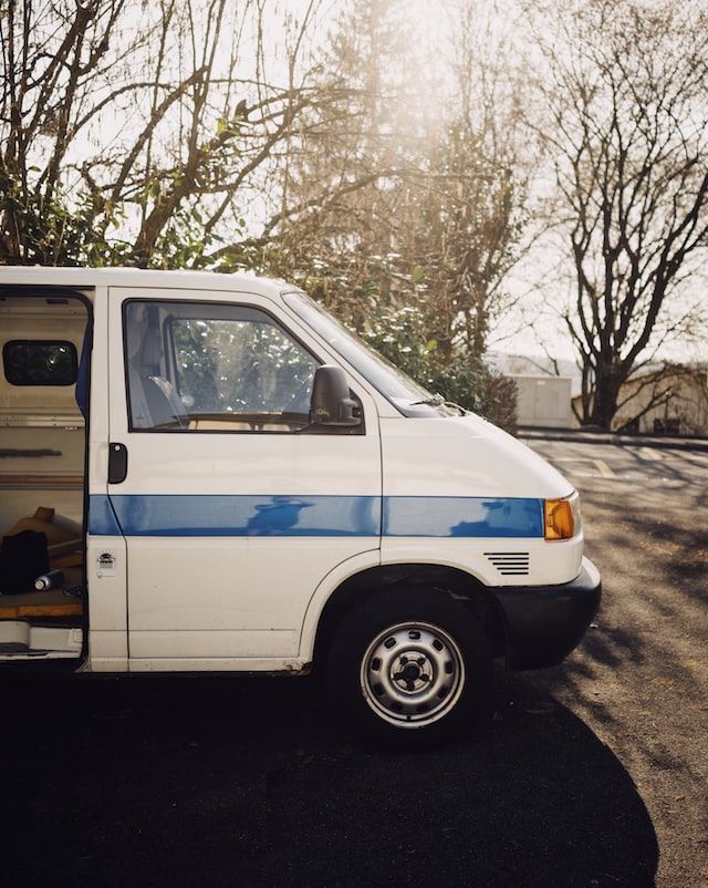 White van with blue stripe, parked outside on a sunny day, door open.