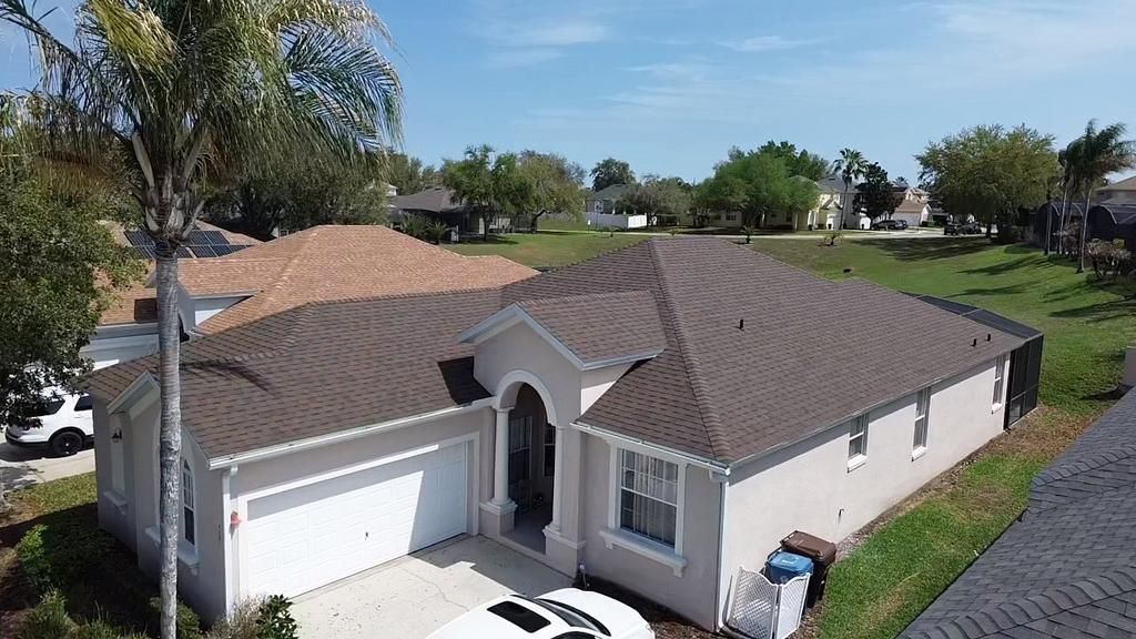 An aerial view of a house with a new gray roof and a garage.