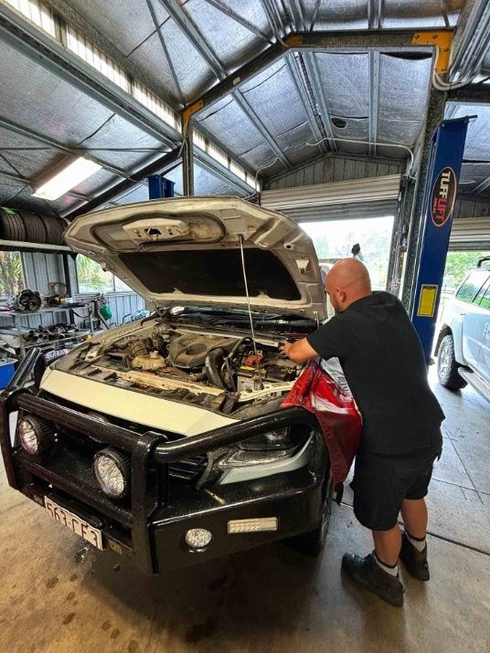 A Man Is Working On The Engine Of A Car In A Garage — Master Mechanix In Yandina Creek, QLD