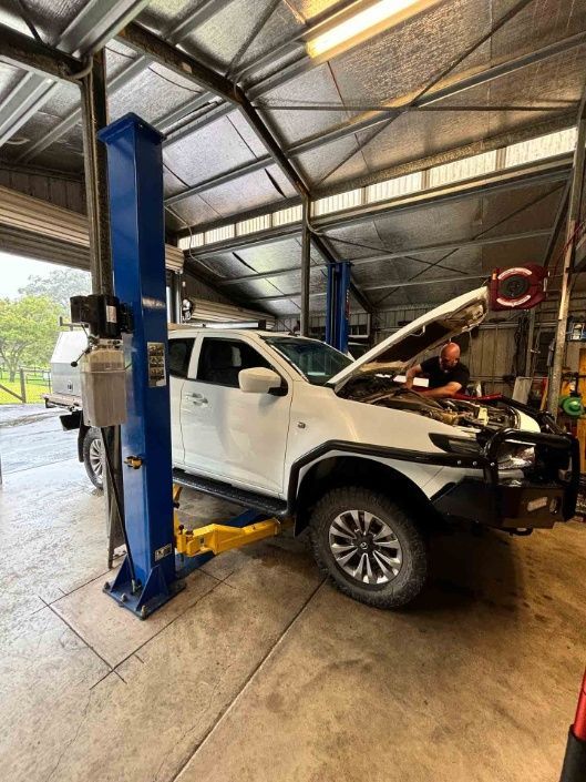 A White Truck Is Sitting On A Lift In A Garage — Master Mechanix In Yandina Creek, QLD