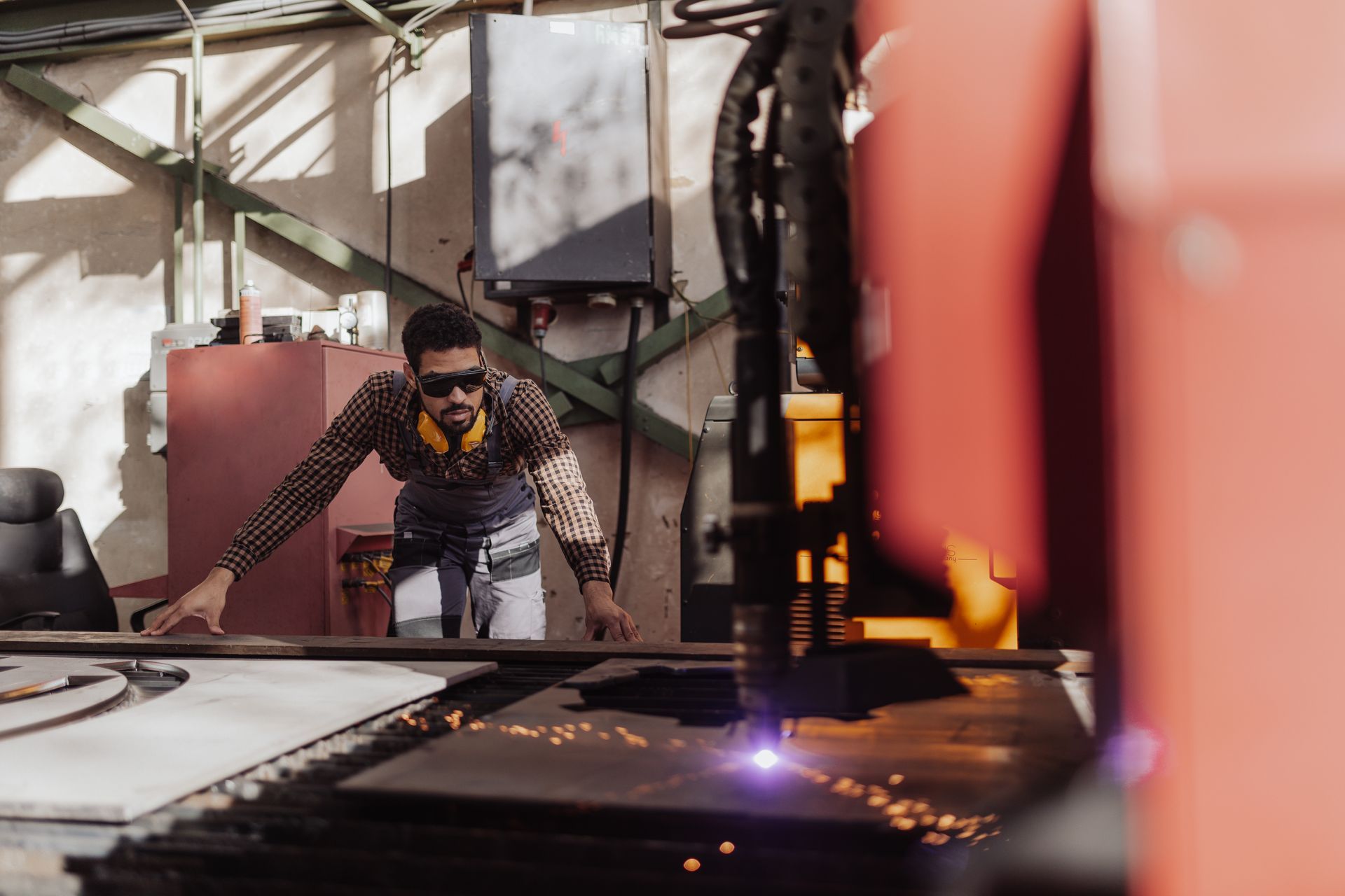 Man working on a laser cutter at a metalworking manufacturing plant