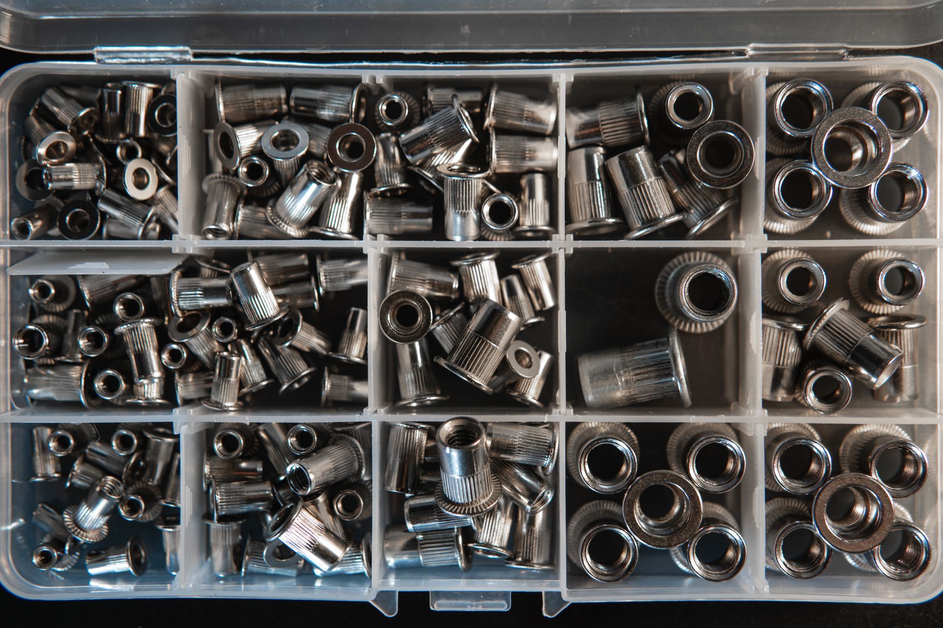A variety of threaded metal rivet inserts neatly organised within a container. A variety of threaded metal rivet inserts neatly organised within a container.