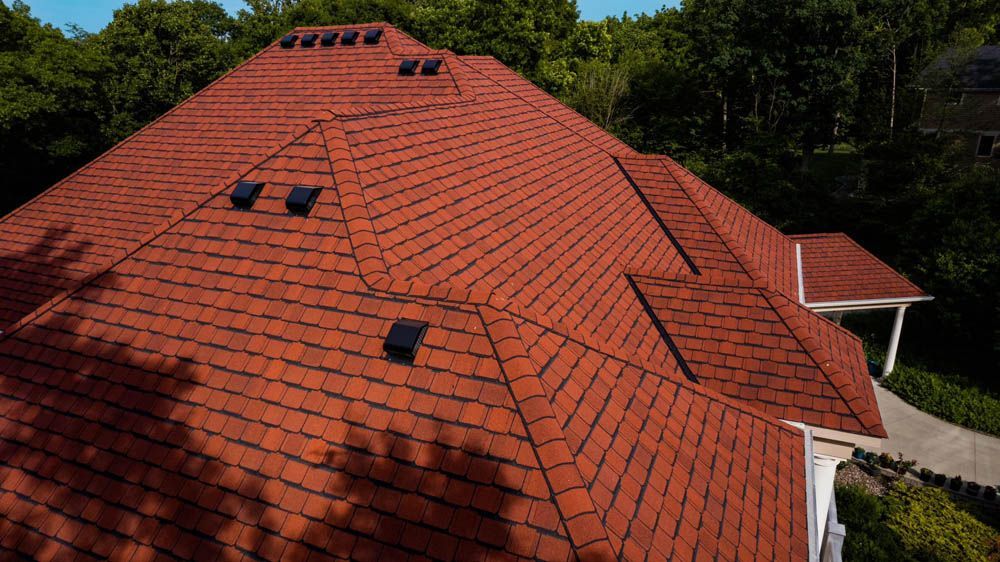 Red tiled roof with skylights and surrounding trees, viewed from above