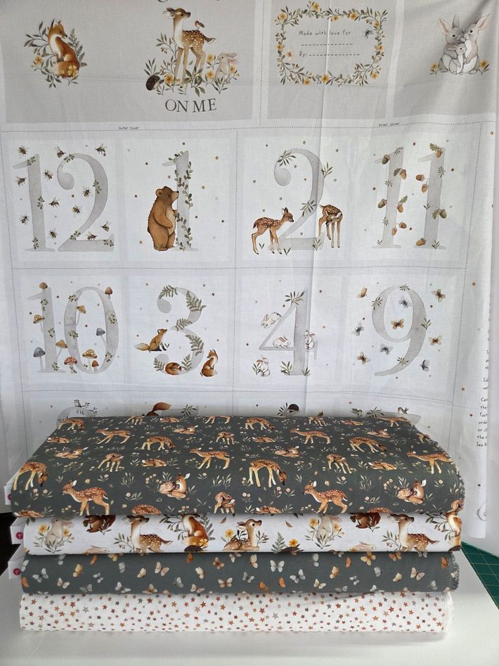 Nursery setup with deer-themed alphabet-and-number wall decals above a patterned changing table