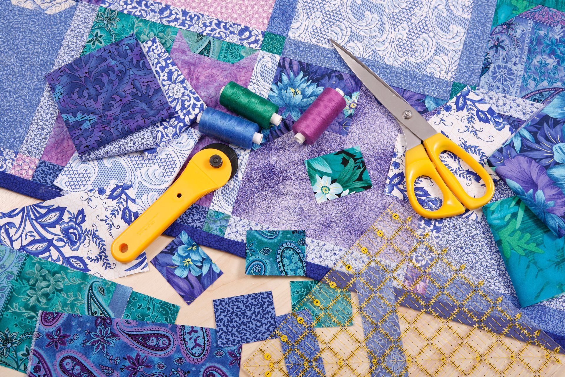 Quilting tools on colorful fabric with scissors and thread.