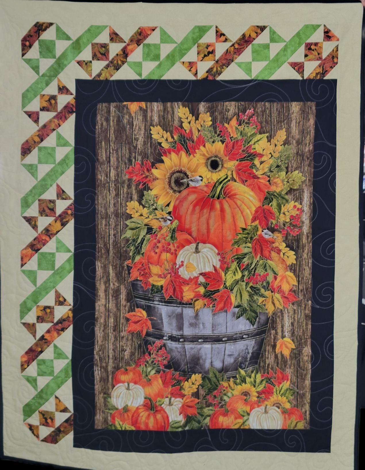 Pumpkin and autumn flowers in a rustic basket within a quilted border
