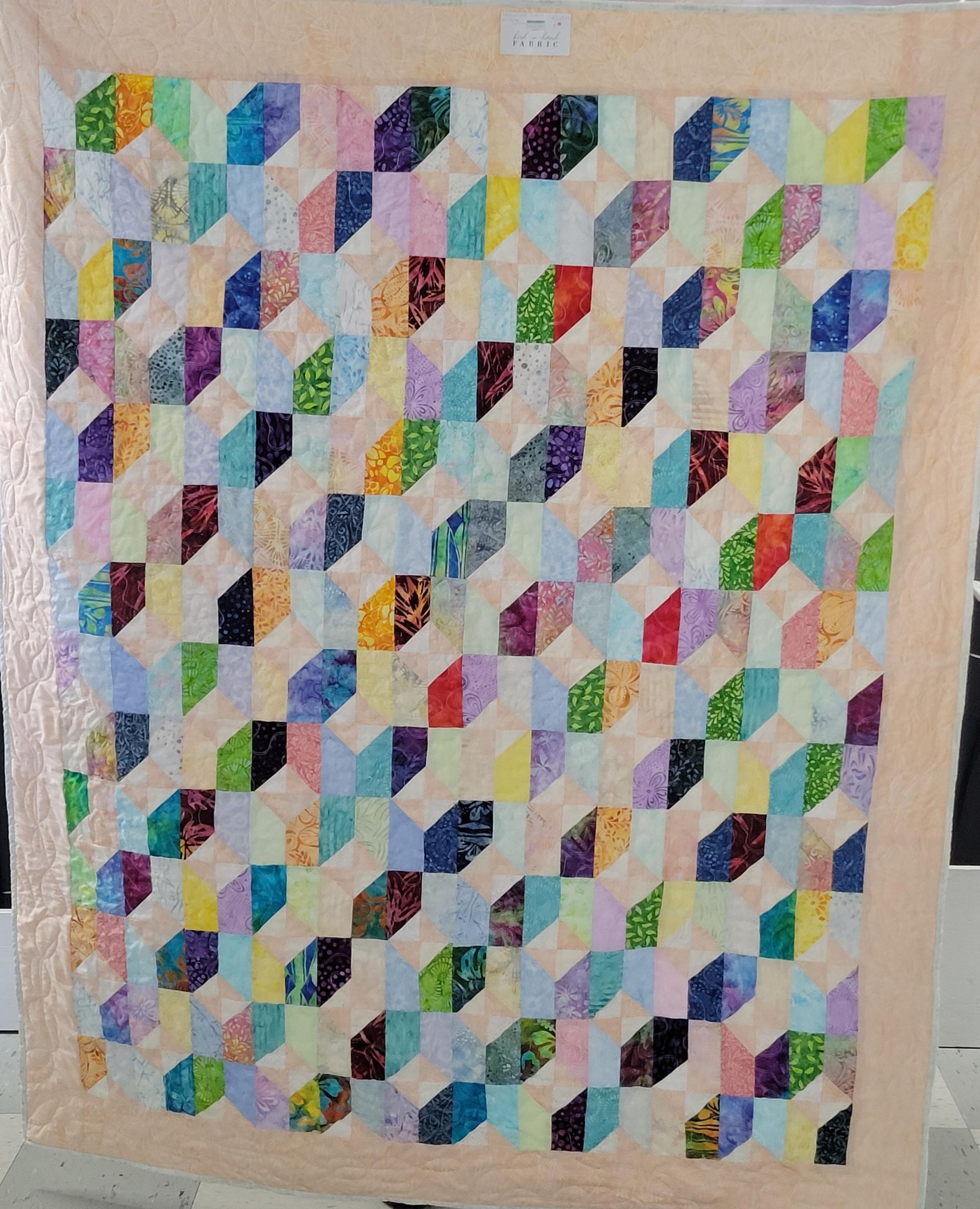 Colorful patchwork quilt with geometric fabric pieces in pastel and bright colors.