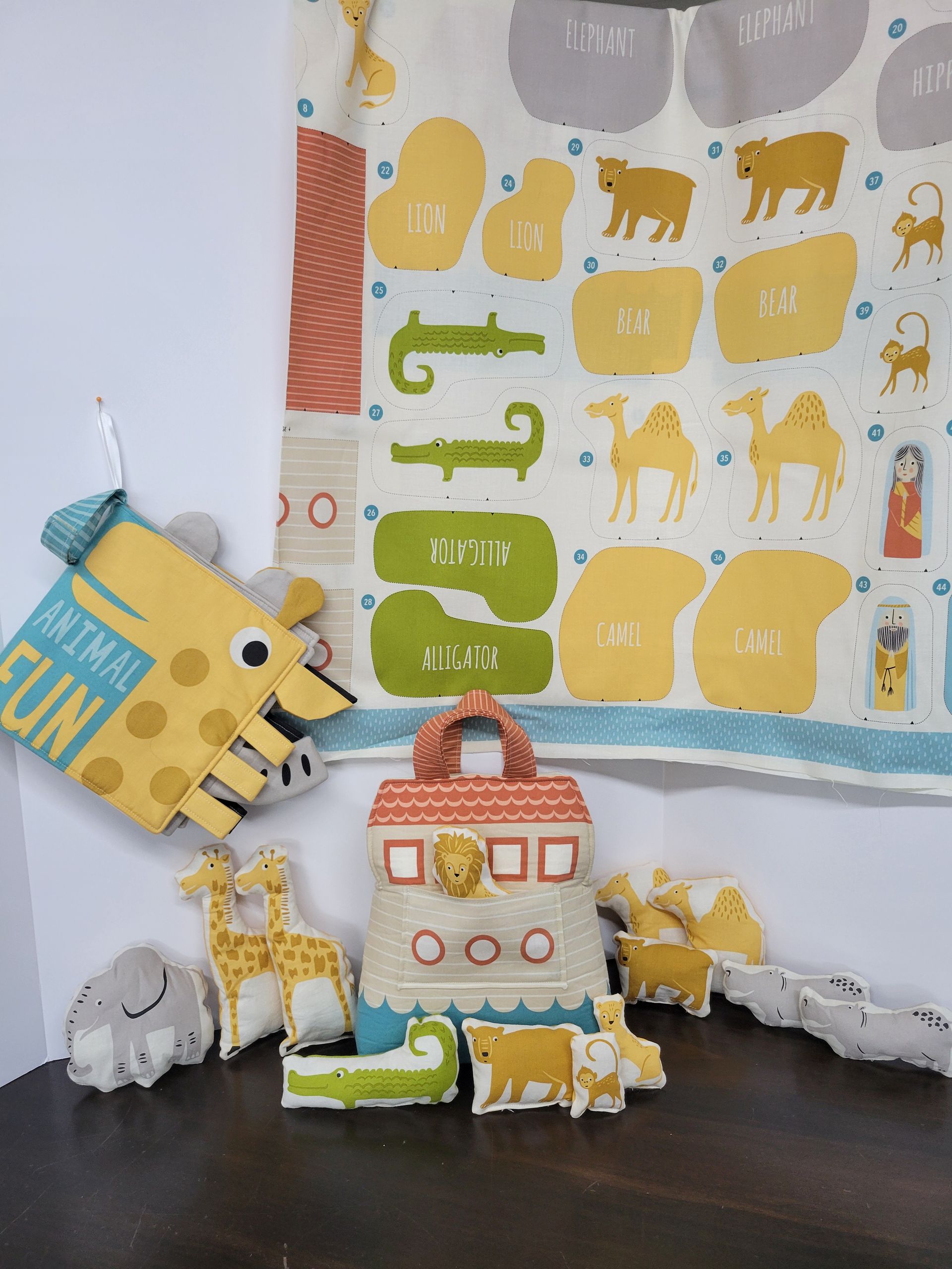 Colorful toy farm animals and a small barn arranged on a dark surface against a patterned nursery backdrop