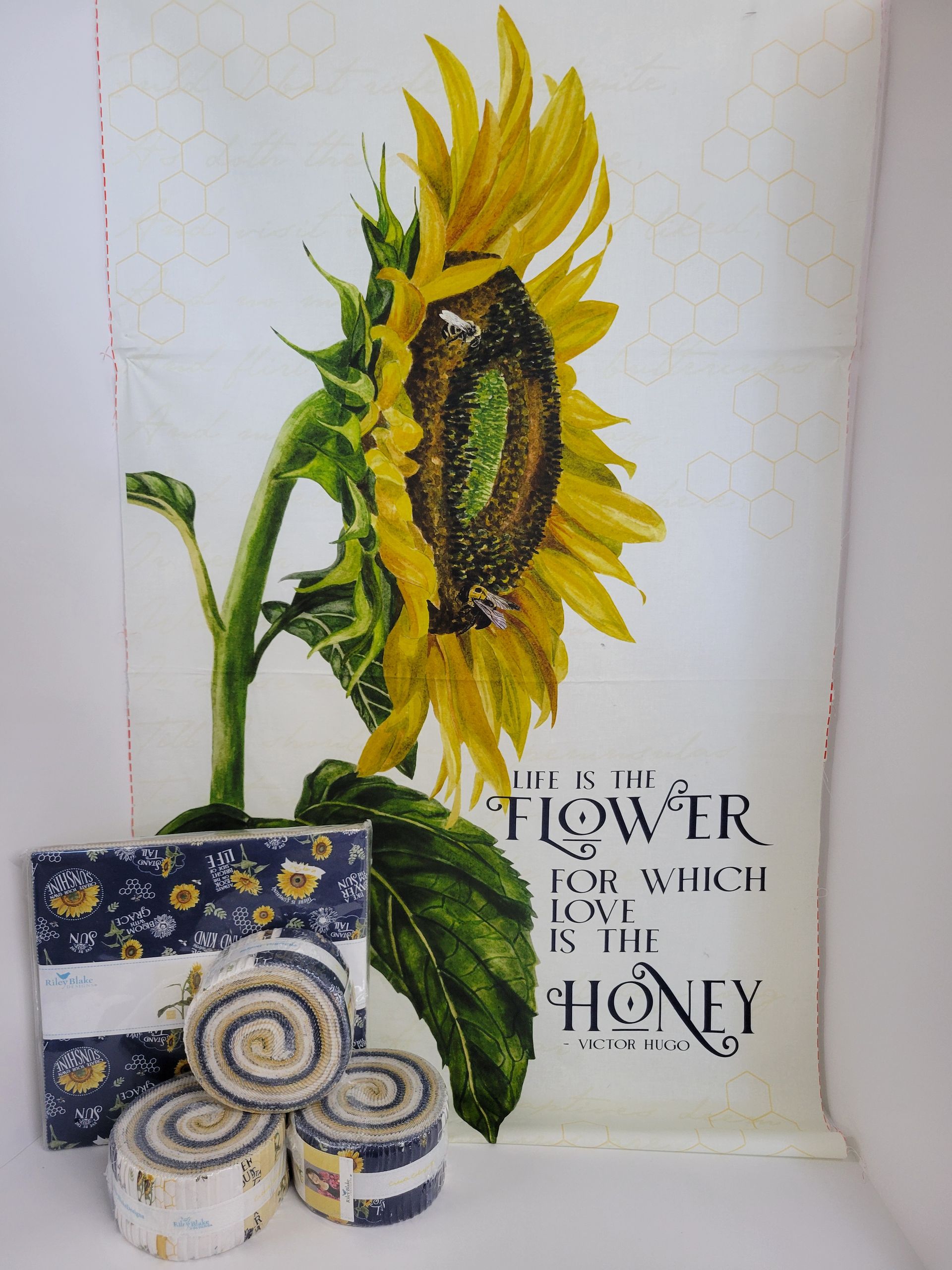 Fabric with a sunflower design and fabric rolls. White background with text: 
