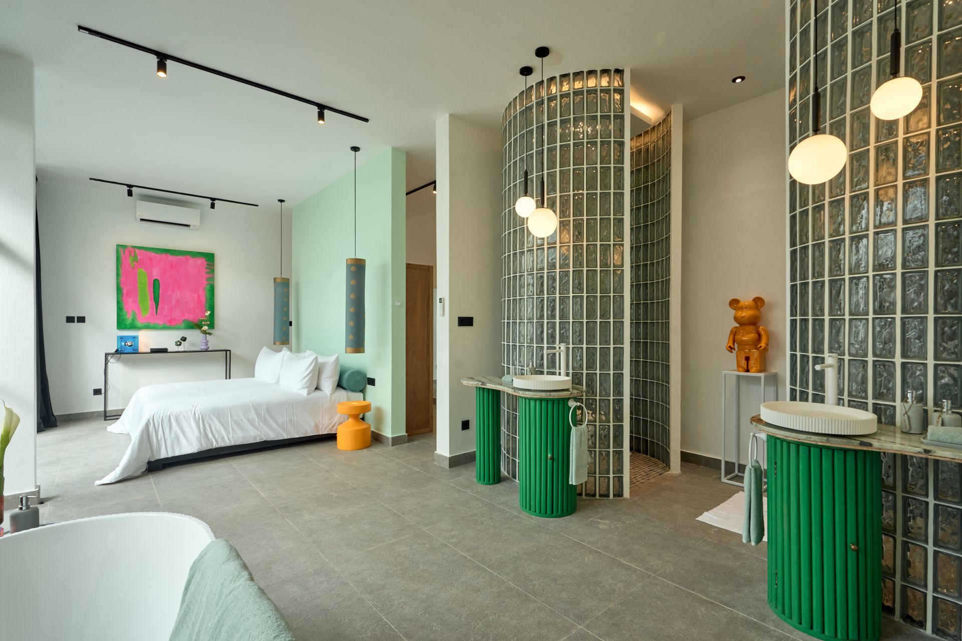 Bright modern hotel room with twin beds, green cabinets, a tiled shower, and colorful wall art