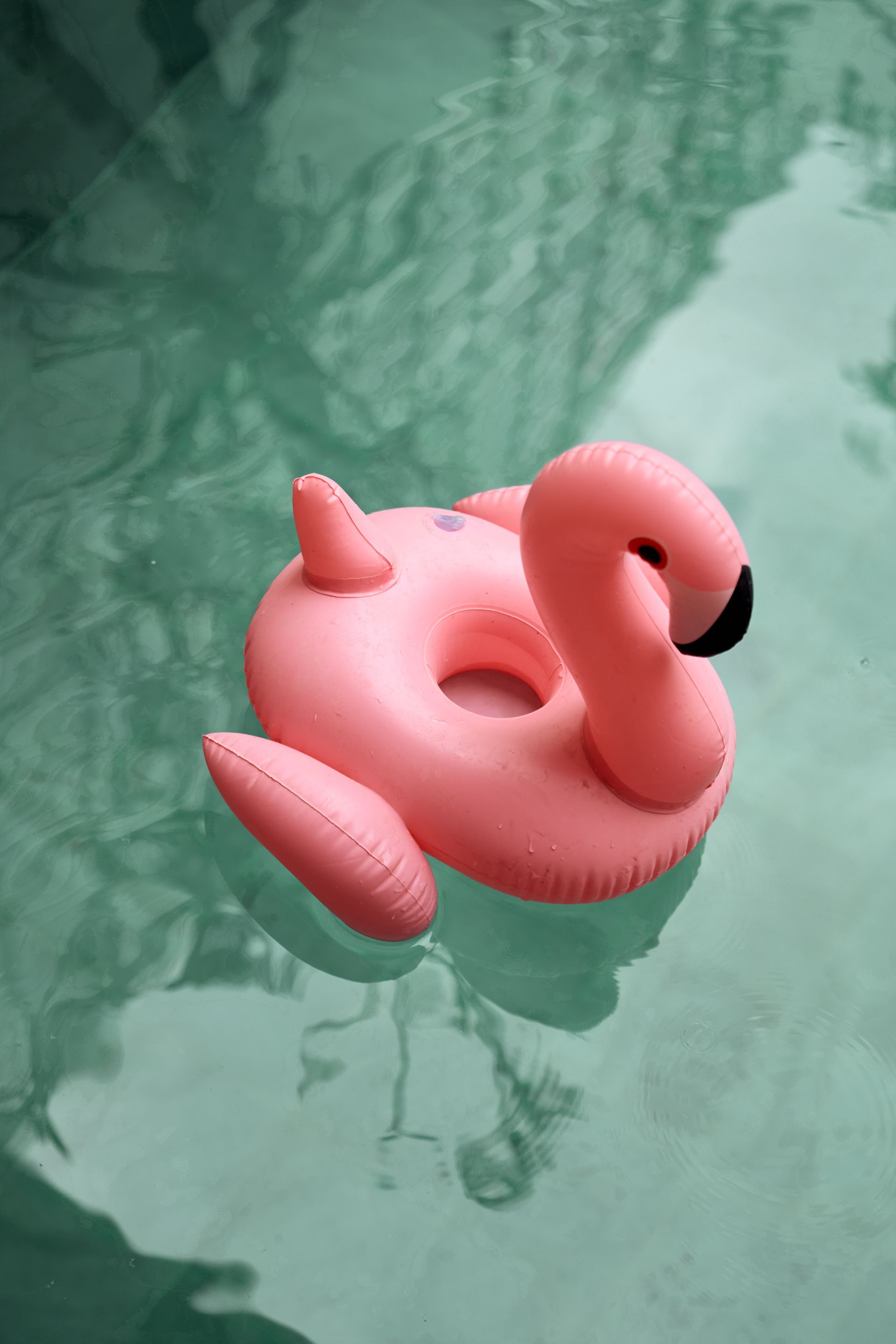Pink flamingo-shaped float on calm green pool water