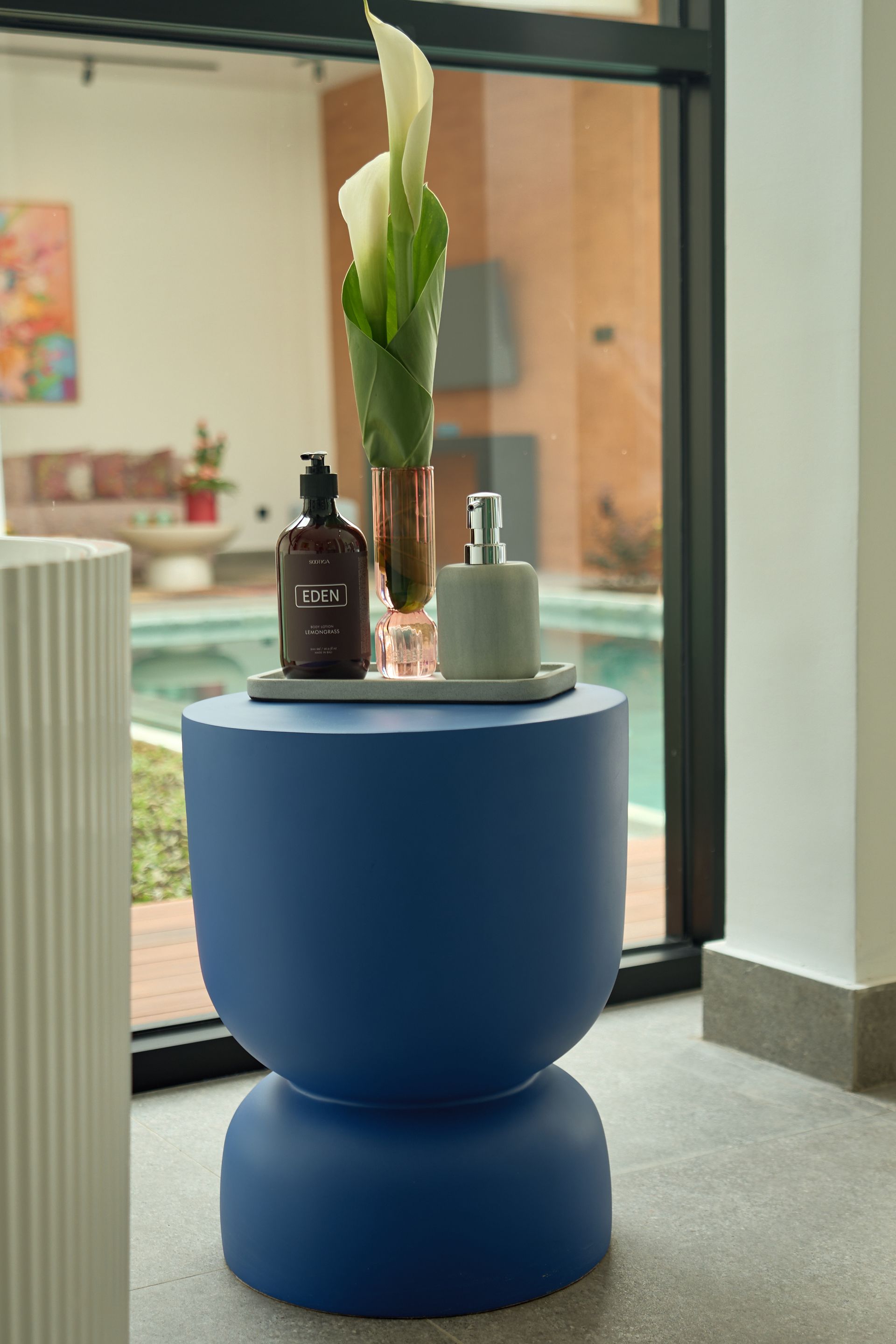Blue round side table with vases and a plant by a window in a modern room