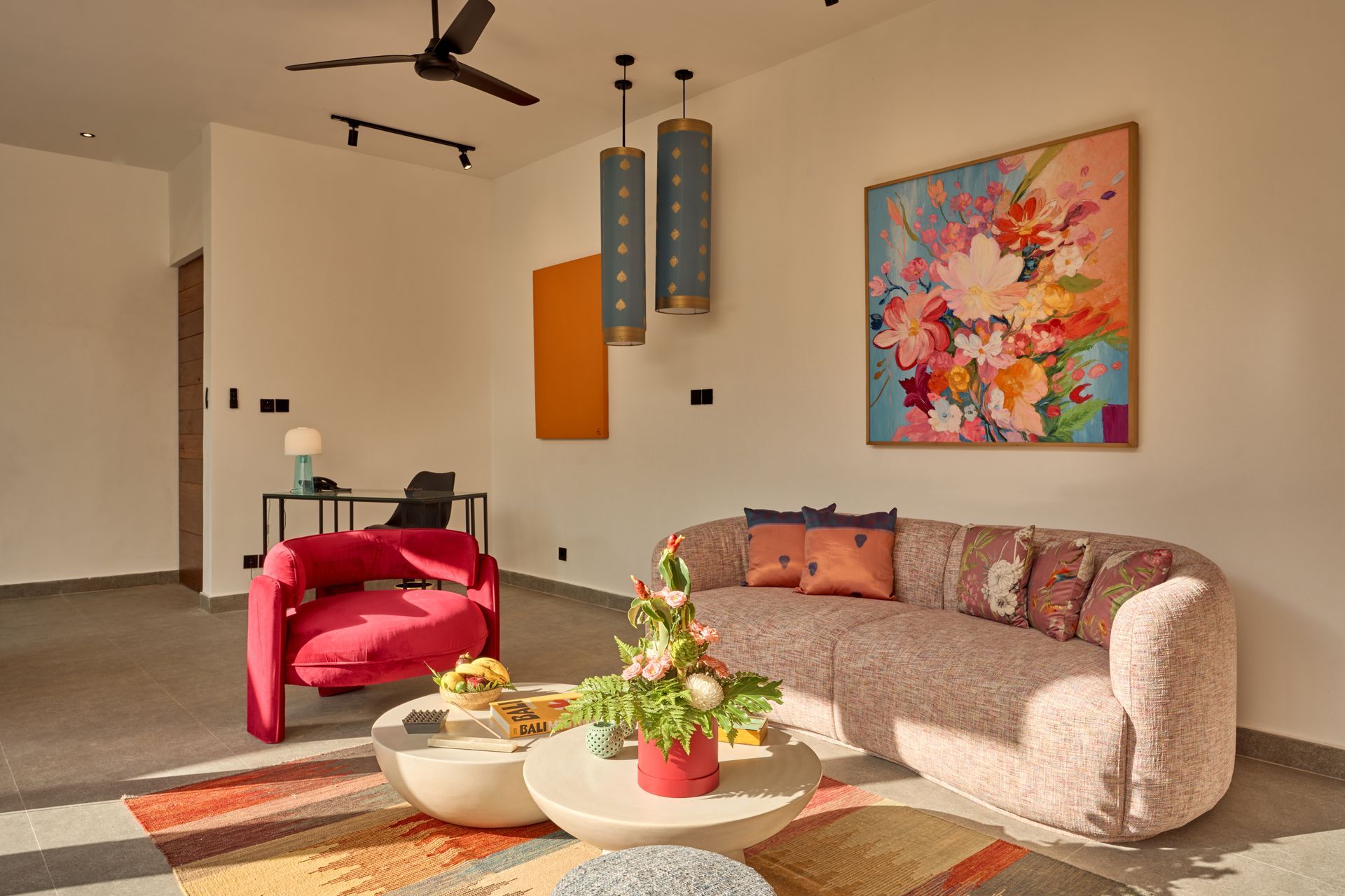 Bright modern living room with a pink chair, beige sofa, colorful abstract art, and a coffee table