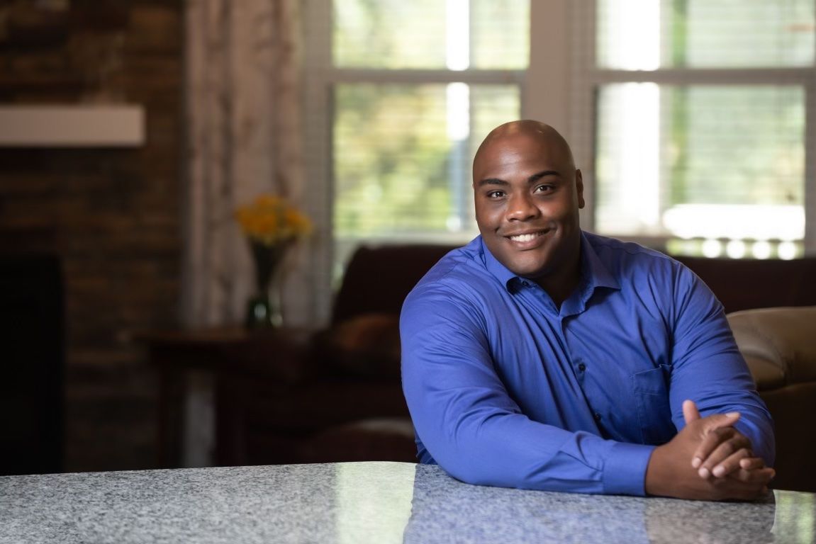a man in a blue shirt sits at a counter with his hands folded- Fred Johnson NC Realtor