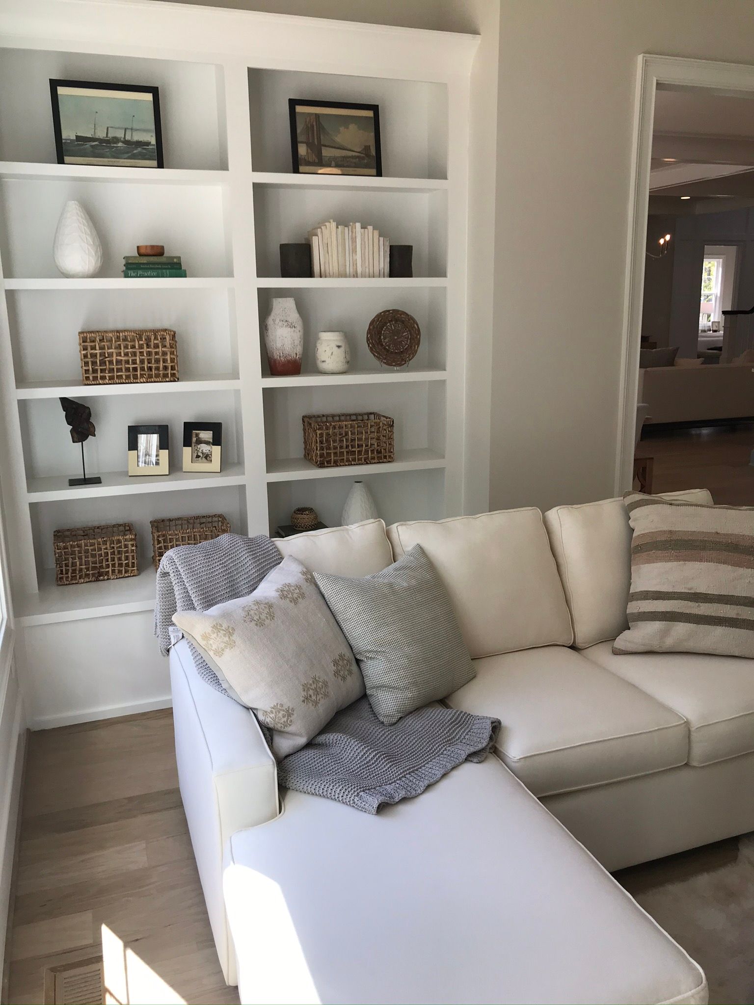 a living room with a white sectional couch and white shelves - HOMEVIBES NC Realty