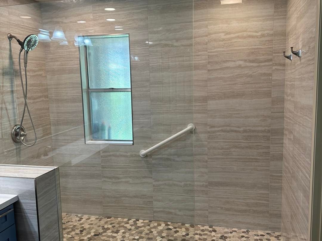 Modern tiled bathroom shower with glass enclosure, window, chrome fixtures, and grab bar