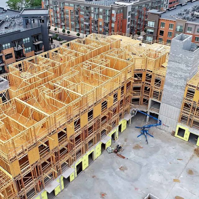 Aerial view of a large wood-framed apartment building under construction in a city courtyard