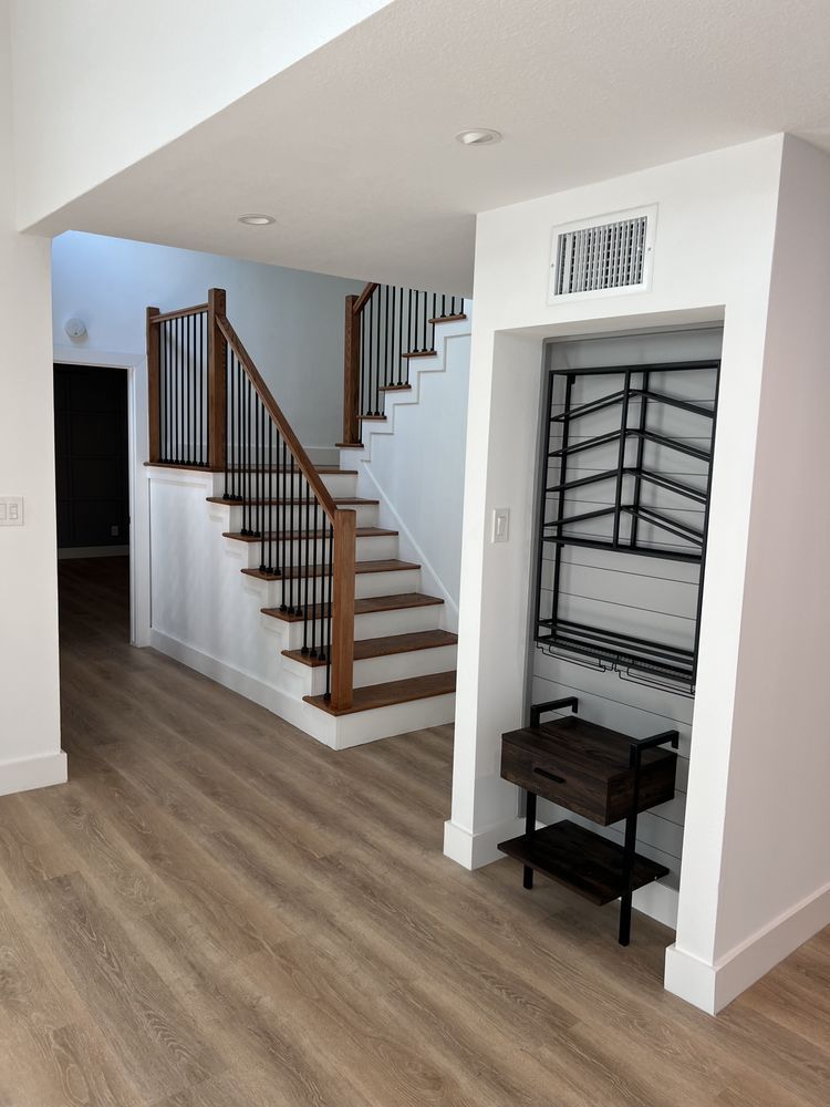 Open living area with stairs, white walls, wood floors, and a built-in shoe rack nook