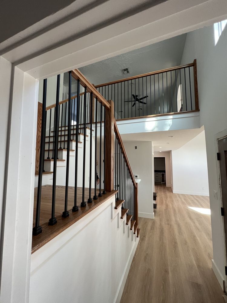 Bright stair hall with black balusters, wood railing, and light wood floors in a modern home