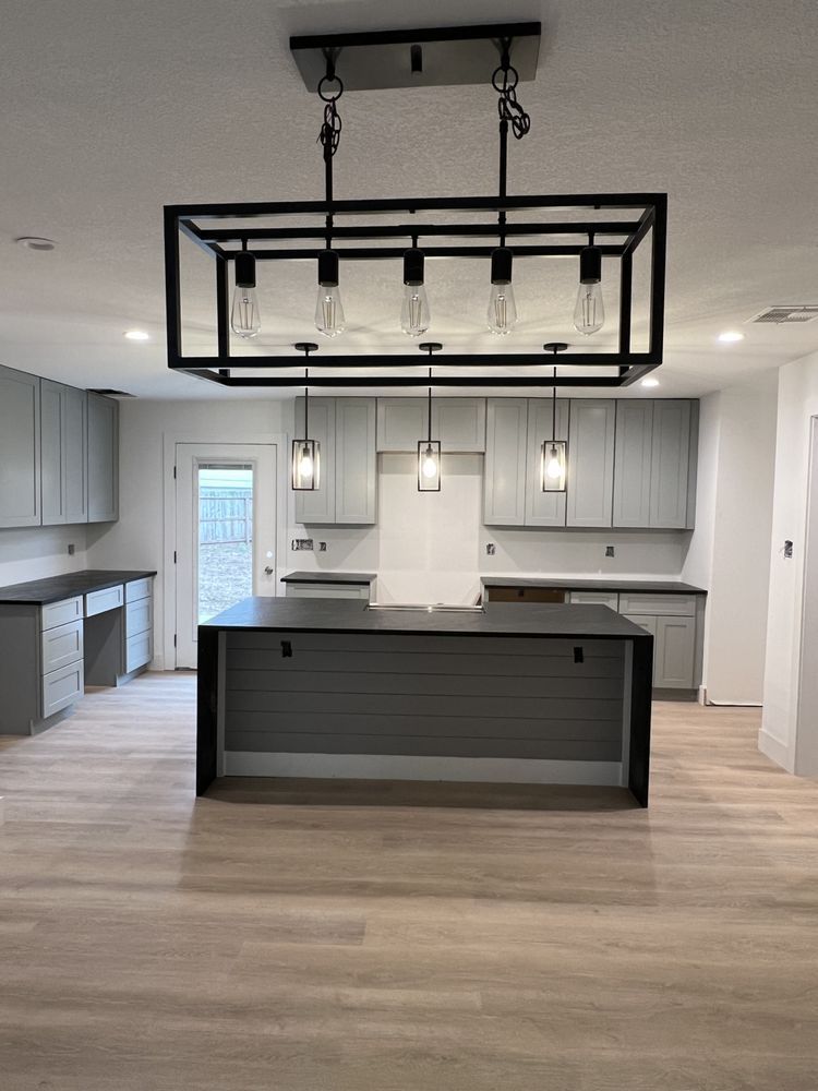 Modern kitchen with gray cabinets, large island, and black rectangular pendant light fixture