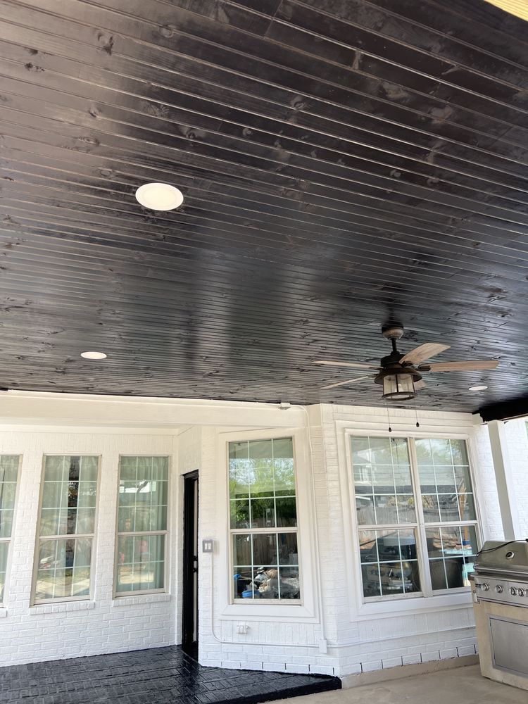 Covered porch with dark beadboard ceiling, white French doors, windows, and a hanging lantern.