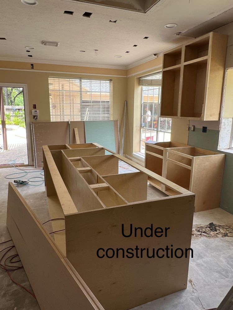 Kitchen under construction with unfinished cabinets, exposed walls, and an open floor plan.
