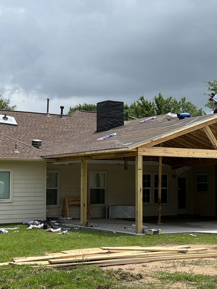 House under construction with new roof framing and porch in overcast weather