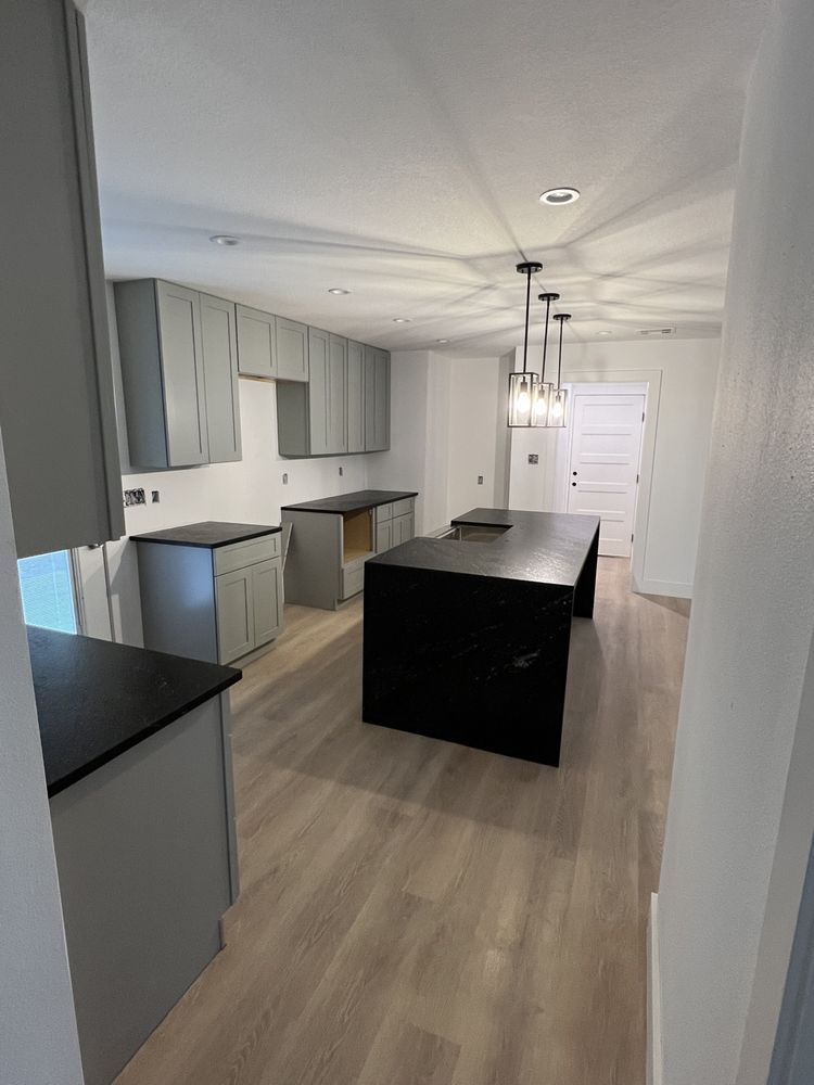 Modern kitchen with white cabinets, black island, and pendant lights under a sloped ceiling
