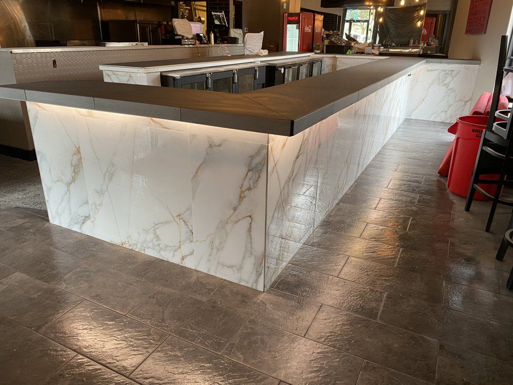 Marble bar counter in a restaurant with dark wood top and tiled floor
