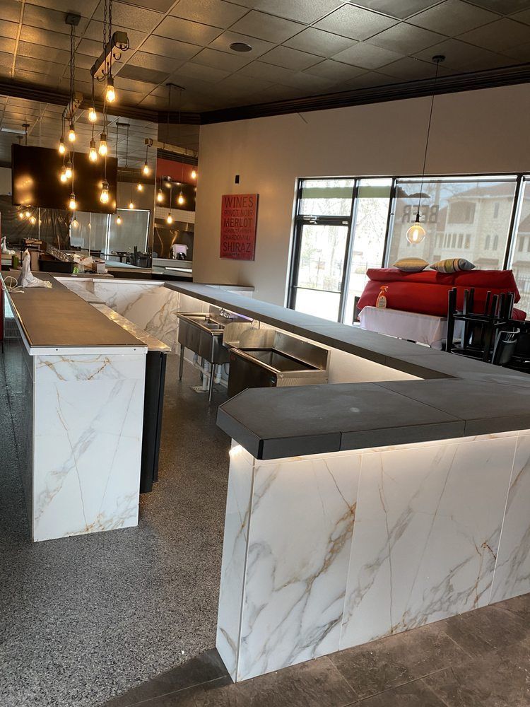Empty modern cafe interior with marble counters, bar stools, and red seating near large windows