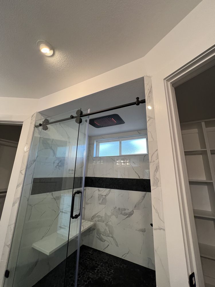 Modern glass shower with black fixtures and marble tile in a tiled bathroom