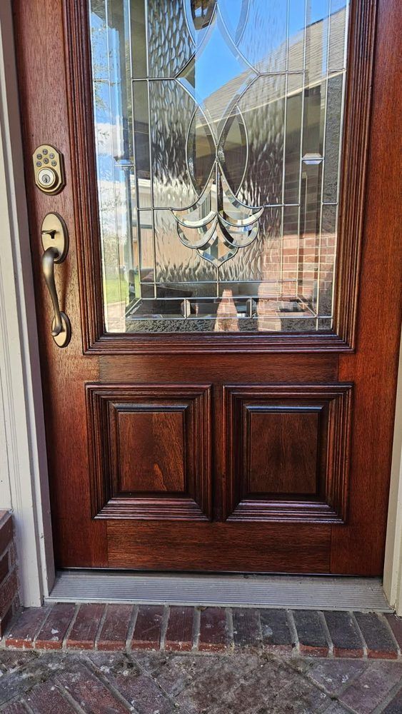Wooden front door with glass panel and brass handle, set in a brick entryway