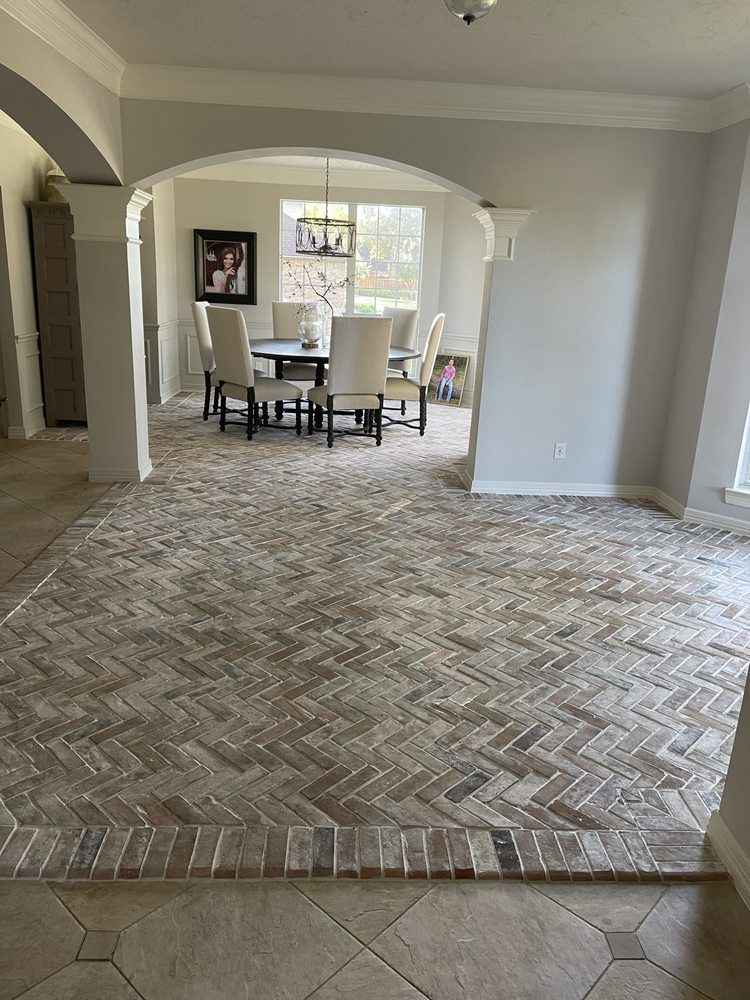 Spacious living room with patterned tile floor, arched openings, and dining table by a bright window.