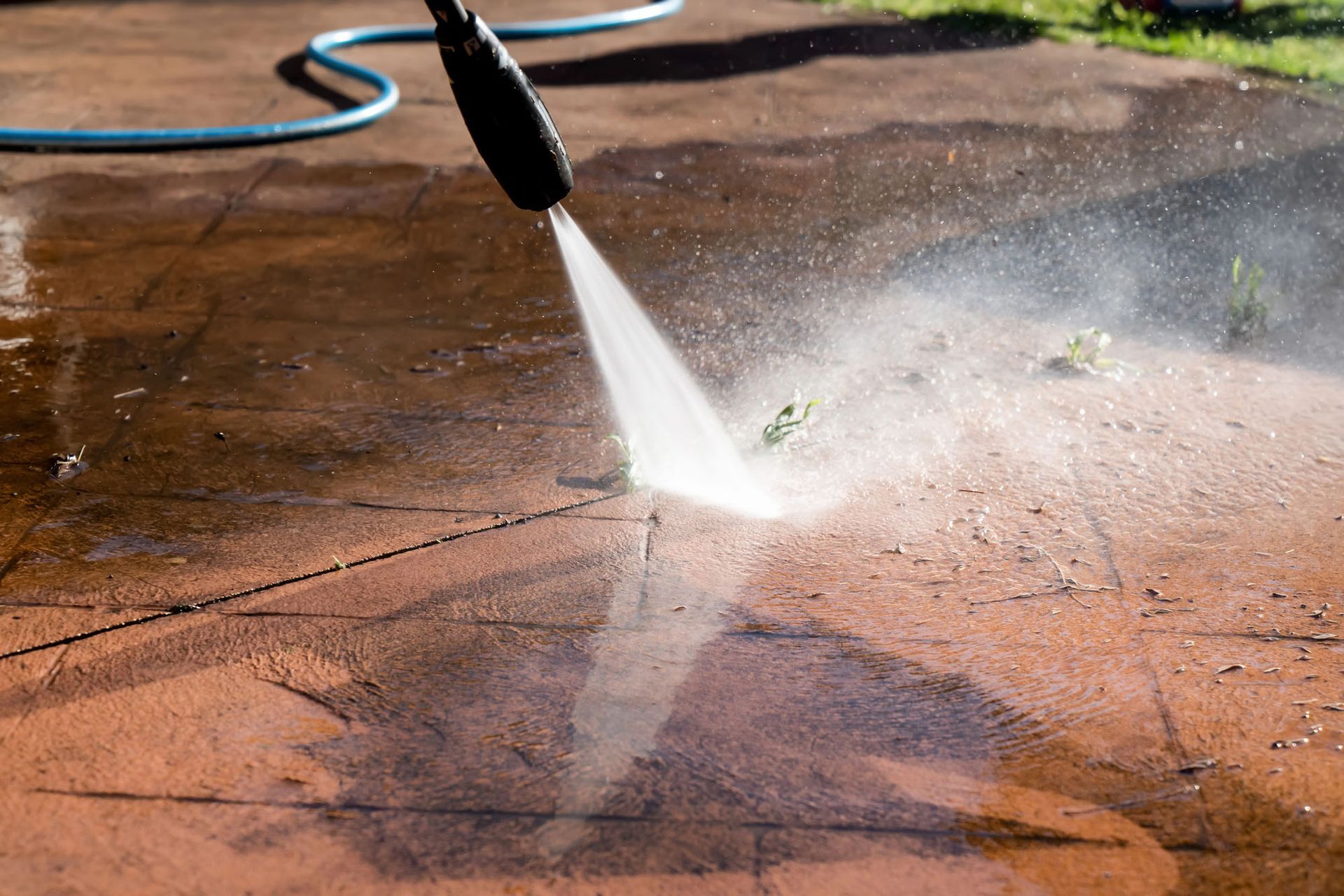 Idropulitrice che spruzza acqua su un vialetto di cemento bagnato, pulendone la superficie