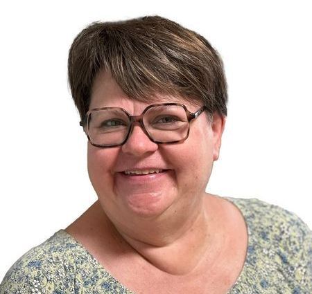 Eine Frau mit Brille und Halskette lächelt in die Kamera
