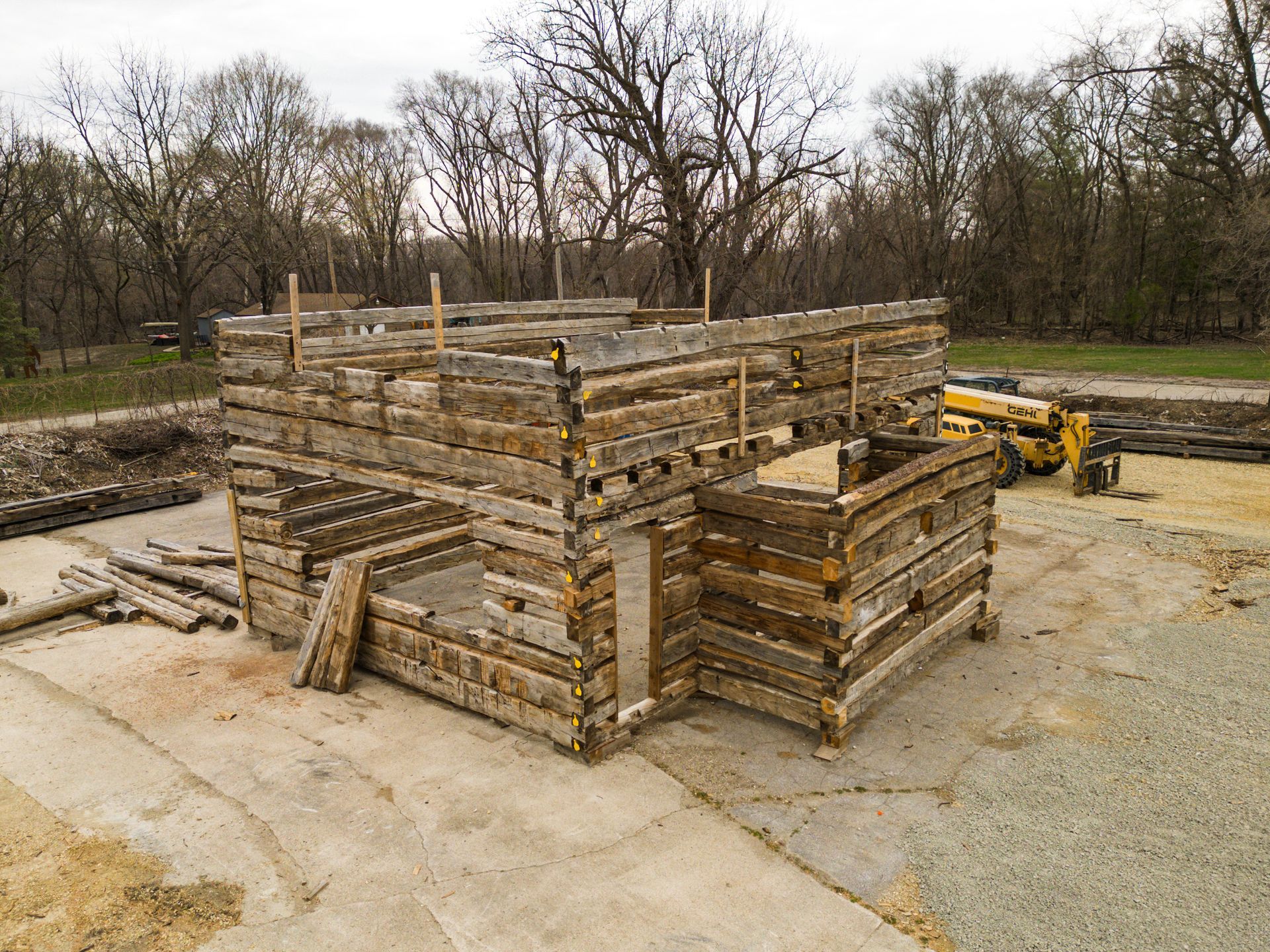 Stacked stone blocks forming a building foundation at a construction site, with a yellow machine nearby.
