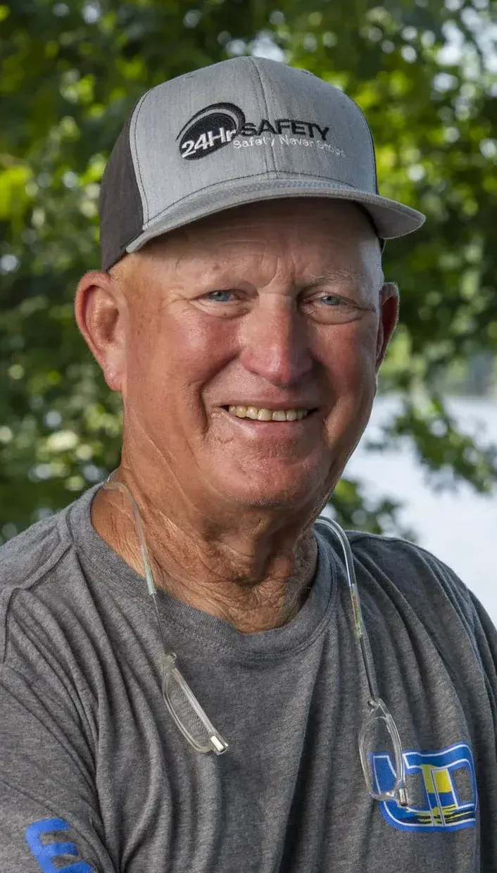 a man wearing a hat and a gray shirt is smiling for the camera .