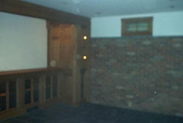 Dim room with a large projection screen, wooden cabinets, and a brick wall.