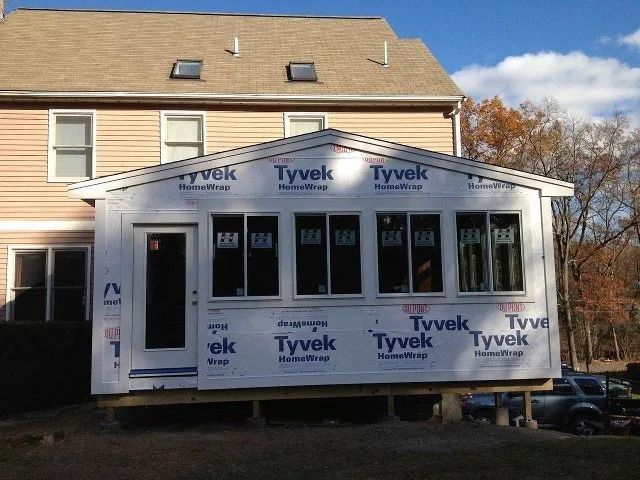 House under renovation with Tyvek wrap and a sunroom addition under construction