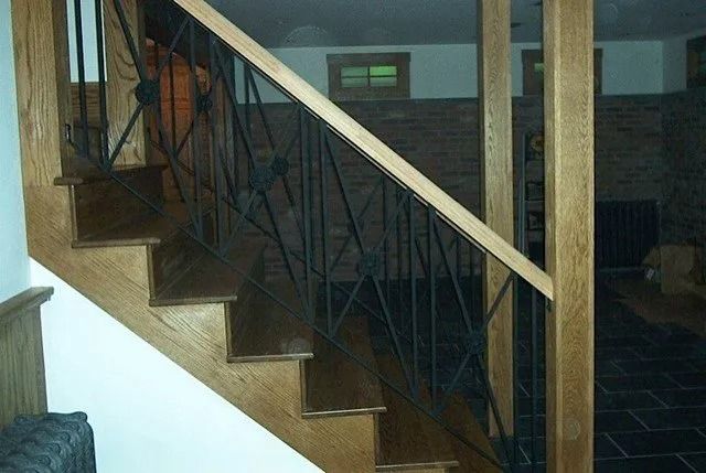Wooden staircase with dark metal railing inside a home interior