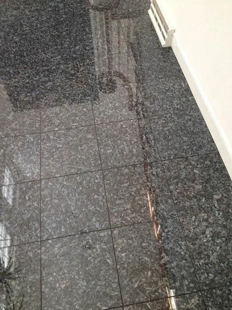 Dark tiled floor with a long crack or seam near a white wall and doorway.