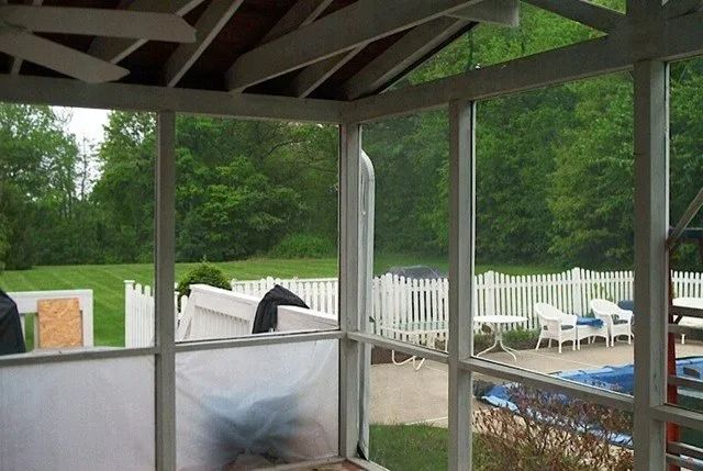 Covered patio overlooking a backyard pool with white fence and green trees