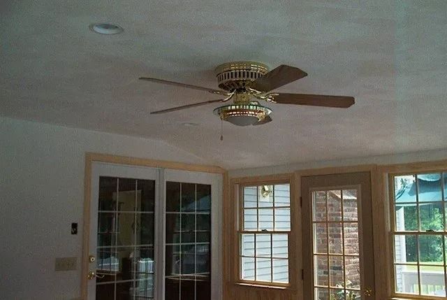 Living room with a ceiling fan, large windows, and beige walls