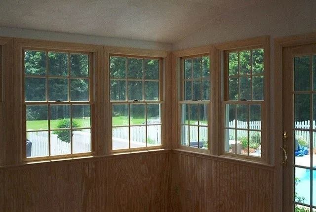 Wood-paneled room with corner windows overlooking a backyard and pool